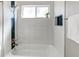 Bright bathroom featuring updated tile work, shower fixtures, a plant, and a built-in soap holder at 280 Birch St, Bennett, CO 80102