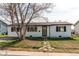 Charming home featuring stone pathway, green door, black trimmed windows, and tidy lawn at 280 Birch St, Bennett, CO 80102