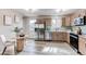 Eat-in kitchen featuring stainless appliances, wood cabinets, modern lighting, and ample sunlight at 280 Birch St, Bennett, CO 80102