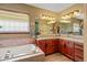 Well-lit bathroom with soaking tub, double sinks, cherry cabinets and walk-in shower at 6699 S Robb St, Littleton, CO 80127