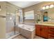 Bright bathroom featuring soaking tub, glass shower, and cherry cabinets at 6699 S Robb St, Littleton, CO 80127