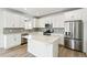 Bright kitchen with white cabinets, island, stainless steel appliances, and wood-look flooring at 1871 Water Birch Way, Castle Rock, CO 80108