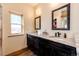 Bathroom featuring double sinks with granite countertops, dark wood cabinets, and a rustic window at 2710 Rustlers Canyon Loop, Elizabeth, CO 80107
