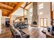 Bright living room with exposed beams, hardwood floors, and a stone fireplace at 2710 Rustlers Canyon Loop, Elizabeth, CO 80107