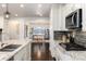 Modern kitchen featuring stainless steel appliances, granite countertops, and an island with a sink and views of an adjacent office area at 16549 Prospect Ln, Broomfield, CO 80023