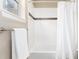 The clean shower features white tiling, a contrasting dark accent stripe, and a modern shower curtain, lit by a nearby window at 16549 Prospect Ln, Broomfield, CO 80023