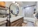 Modern bathroom with vanity, large round mirror, tiled shower, and good natural light at 12131 Melody Dr # 201, Denver, CO 80234