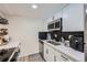 Modern kitchen with white cabinets, stainless steel appliances, herringbone backsplash, and a view of the living area at 12131 Melody Dr # 201, Denver, CO 80234