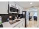 Well-lit kitchen featuring white cabinets, stainless steel microwave, and herringbone backsplash at 12131 Melody Dr # 201, Denver, CO 80234