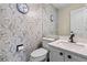 Stylish half bathroom features decorative wallpaper, marble countertops, and a modern toilet at 20349 E Powers Pl, Centennial, CO 80015