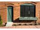 Close-up of a green front door, window, and brick facade, with a flower box, offering vintage charm at 2801 Champa St, Denver, CO 80205