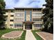 Inviting condo complex featuring a manicured lawn, mature trees, and charming architectural details at 9155 E Center Ave # 4B, Denver, CO 80247