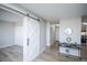 Hallway features a stylish sliding barn door, light wood floors, and a console table with decorative accents at 9155 E Center Ave # 4B, Denver, CO 80247