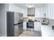 A modern kitchen with white cabinets, stainless steel appliances, and light wood floors at 9155 E Center Ave # 4B, Denver, CO 80247