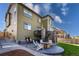 A spacious backyard with a patio, outdoor dining, stone fireplace, steps to deck, and lush green grass at 12841 Galapago St, Westminster, CO 80234