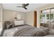 Comfortable bedroom featuring soft carpet, a ceiling fan, a large window, and closet; virtually staged at 18445 W 59Th Dr, Golden, CO 80403