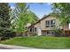 Inviting exterior showcasing a well-maintained lawn and charming stone accents, with abundant mature trees for shade at 18445 W 59Th Dr, Golden, CO 80403