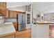 Modern kitchen featuring stainless steel appliances, oak cabinets, and a breakfast bar, seamlessly connecting to the living room at 18445 W 59Th Dr, Golden, CO 80403