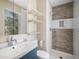 Bright bathroom featuring modern sink, toilet, and shower with rustic wood accent wall, and floating shelves at 19876 E Brunswick Dr, Aurora, CO 80013