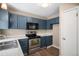 The kitchen boasts stainless steel appliances, a built-in microwave, and blue cabinets at 19876 E Brunswick Dr, Aurora, CO 80013