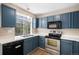 This kitchen features stainless steel appliances, a stainless sink, and plenty of storage in blue cabinets at 19876 E Brunswick Dr, Aurora, CO 80013