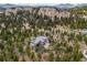 Wide aerial view of home nestled amongst mature trees and rock outcroppings, featuring a private driveway at 6767 Timbers Dr, Evergreen, CO 80439