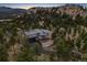 Expansive aerial view of an estate nestled amongst trees, featuring a private drive and mountain views at 6767 Timbers Dr, Evergreen, CO 80439