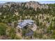 Wide aerial view of home amongst mature trees and rock outcroppings, with a private driveway at 6767 Timbers Dr, Evergreen, CO 80439