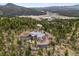 Scenic aerial view of a luxury estate surrounded by lush forest, featuring a long driveway at 6767 Timbers Dr, Evergreen, CO 80439