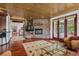 Cozy living room boasts a stone fireplace, wood ceiling and floors, an area rug, and access to an outdoor deck at 6767 Timbers Dr, Evergreen, CO 80439