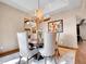 A dining room features a antler chandelier, upholstered chairs, hardwood floors, and access to other rooms and view at 1374 Crested Butte Ct, Evergreen, CO 80439