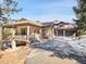 A luxurious residence boasts a three-car garage and an inviting covered porch with stone supports and detailed wood railing at 1374 Crested Butte Ct, Evergreen, CO 80439