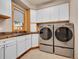 Modern laundry room equipped with front-load washer and dryer, sleek countertops and ample cabinet space at 1374 Crested Butte Ct, Evergreen, CO 80439