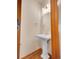 Bright powder room featuring a pedestal sink, round mirror, stylish lighting, and wood floors at 1374 Crested Butte Ct, Evergreen, CO 80439