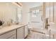 Bright bathroom with white cabinets, white tiled walls, and an accessible shower and tub at 8843 W Phillips Dr, Littleton, CO 80128