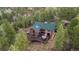 Scenic aerial view of a secluded log home surrounded by lush greenery and towering trees at 6241 Kilimanjaro Dr, Evergreen, CO 80439