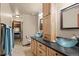 Bathroom featuring dual glass vessel sinks, a tall cabinet, and stone tile flooring at 6241 Kilimanjaro Dr, Evergreen, CO 80439