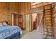 Cozy bedroom featuring wooden walls, private bath, and rustic sliding barn door leading to a unique ladder access at 6241 Kilimanjaro Dr, Evergreen, CO 80439