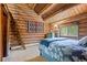Charming bedroom features a rustic log wall, a sliding barn door, and a serene decor at 6241 Kilimanjaro Dr, Evergreen, CO 80439