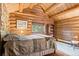 Cozy log bedroom features a rustic aesthetic and inviting warm, natural light at 6241 Kilimanjaro Dr, Evergreen, CO 80439