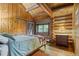 Charming bedroom featuring wood-paneled walls, exposed beam ceiling, and natural light from window at 6241 Kilimanjaro Dr, Evergreen, CO 80439