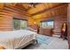 Bright bedroom with log walls, two dressers, a ceiling fan and great views at 6241 Kilimanjaro Dr, Evergreen, CO 80439