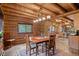 Dining room open to the kitchen, featuring log walls and an adjacent stainless steel appliance filled kitchen at 6241 Kilimanjaro Dr, Evergreen, CO 80439
