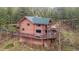 Stunning exterior view of a log home with a large deck, set amidst a forest backdrop, and an elevated foundation at 6241 Kilimanjaro Dr, Evergreen, CO 80439