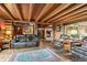 Inviting living room featuring log walls, hardwood floors, comfortable leather sofas, and a rustic stone fireplace at 6241 Kilimanjaro Dr, Evergreen, CO 80439