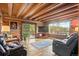 Cozy living room with log walls, hardwood floors, leather recliners, and glass patio doors to a deck with mountain views at 6241 Kilimanjaro Dr, Evergreen, CO 80439
