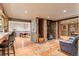 Cozy living room featuring wood floors, stone fireplace, and bar area leading to office and dining at 6241 Kilimanjaro Dr, Evergreen, CO 80439