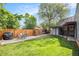 Serene backyard featuring a patio, green lawn, a greenhouse, and mature trees at 2595 S Irving St, Denver, CO 80219