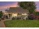 Cozy home exterior with a green lawn, a seating area, and blooming purple flowers, bathed in evening light at 2595 S Irving St, Denver, CO 80219