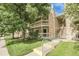 Inviting two-story condo featuring a charming balcony, stone accents, and lush green landscaping at 8225 Fairmount Dr # 102, Denver, CO 80247